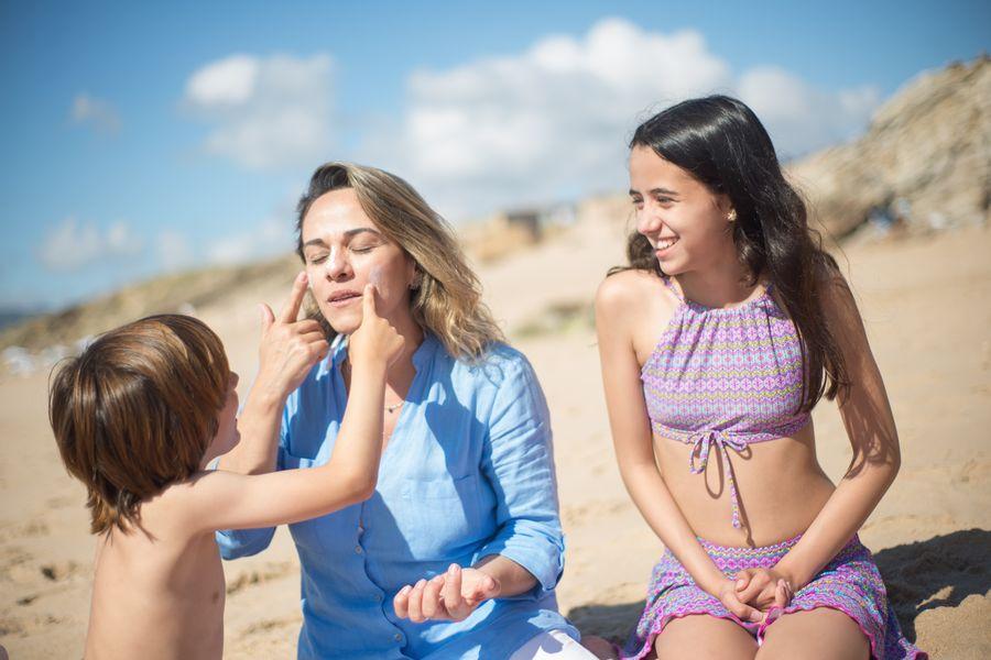 Mulher a aplicar protector solar na praia